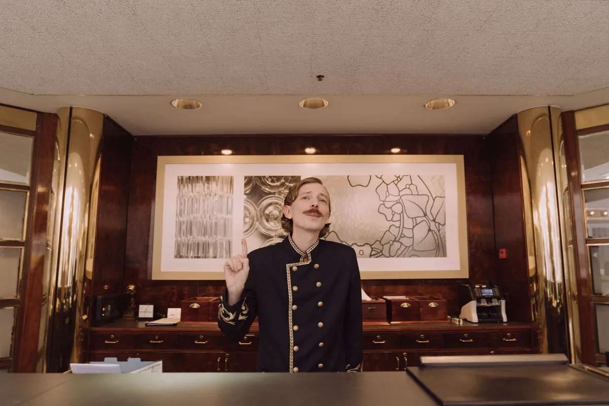 Reception staff assisting a guest in a hotel lobby.